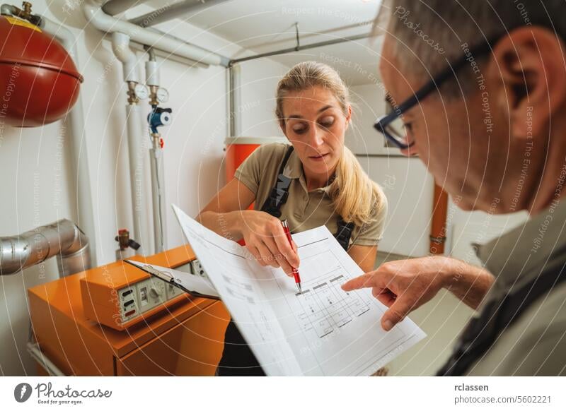 Ein Team von Heizungsmonteuren überprüft eine alte Gasheizung mit einer Papieranleitung in einem Heizungsraum in einem Haus. Gasheizung Ersatz Verpflichtung Konzept Bild