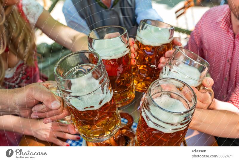 Gruppe glücklicher Freunde, die auf dem bayerischen Oktoberfest Bier trinken und darauf anstoßen brezen Deutsch Bayern Bar Feier jubelt Mann Dirndl Lagerbier