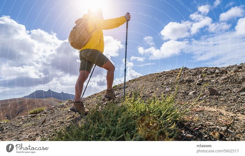 Wanderer mit Rucksack und Trekkingstock beim Aufstieg auf einem Bergpfad unter bewölktem Himmel Fuerteventura Bergweg Besteigung bewölkter Himmel wandern