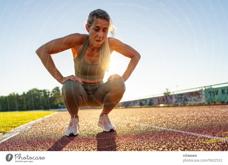 Müde Sportlerin ruht sich nach dem Training auf dem Sportplatz aus aussruhen Leichtathletik Erschöpfung Sportbekleidung Fitness aktiver Lebensstil Atem