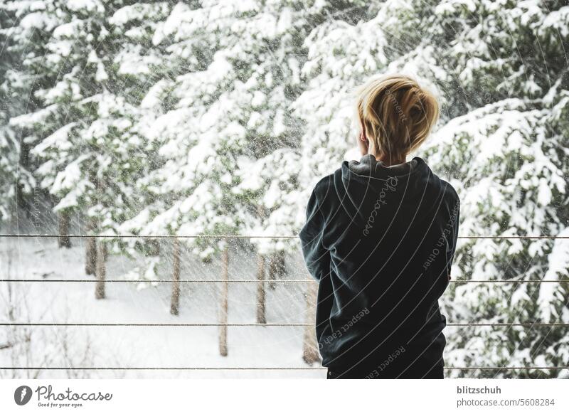 Ein Junge am Fenster beobachtet den Schneefall Winter kalt weiß Natur Winterstimmung Wintertag Schneelandschaft Jahreszeiten Kälte Wald Winterwald Mädchen