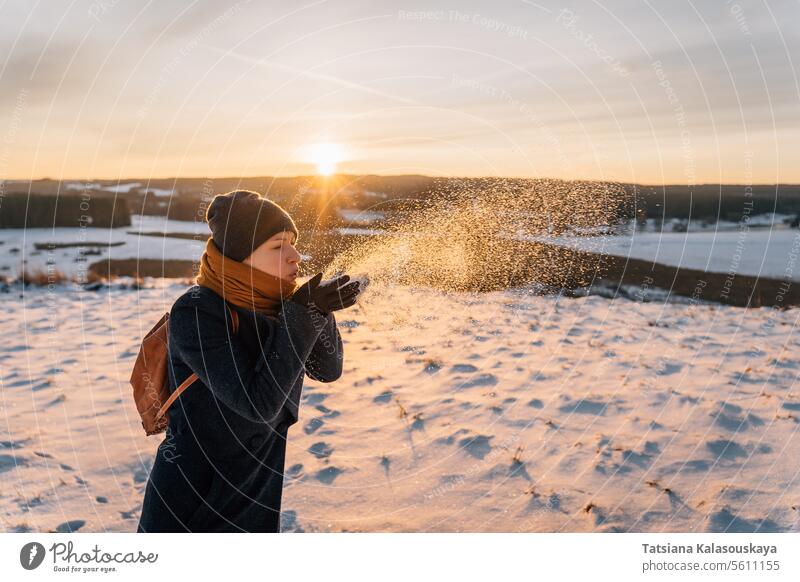 Eine Frau auf einer verschneiten Winterwiese bläst sich den Schnee von den Handflächen Schlag Feld Menschen Person Europäer weiß Erwachsener Halt