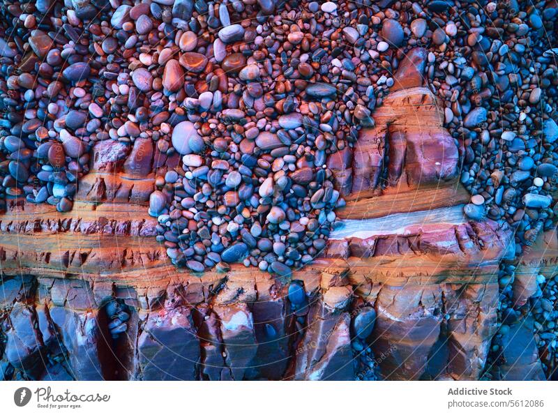 Kieselsteine auf geschichtetem Sedimentgestein sedimentär Felsen Ebene natürlich Textur Stein Geologie Mineral Erde Muster Küstenlinie Ufer farbenfroh