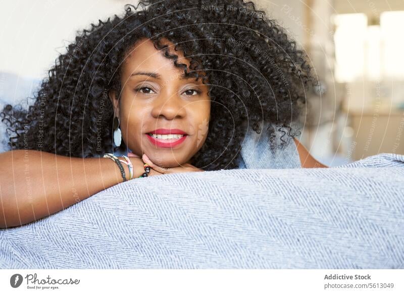 Frau mit lockigem Haar auf Sofa schön Lügen Nahaufnahme Porträt Afro-Look Frisur Wohnzimmer selbstbewusst Windstille sich[Akk] entspannen heimwärts Liege