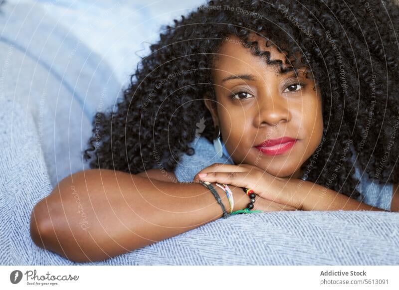 Frau mit lockigem Haar auf Sofa schön Lügen Nahaufnahme Porträt Afro-Look Frisur Wohnzimmer selbstbewusst Windstille sich[Akk] entspannen heimwärts Liege