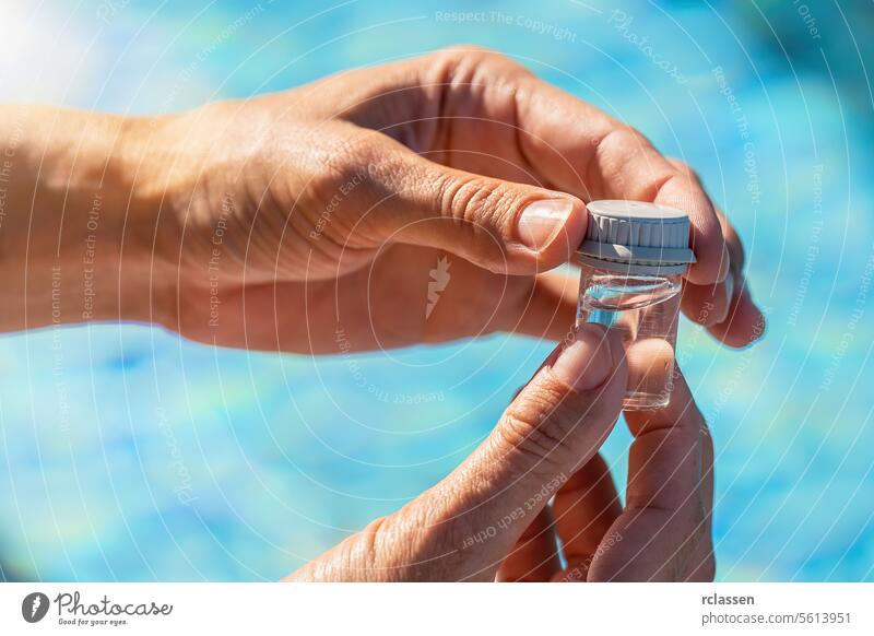 Nahaufnahme Hände, die ein Fläschchen mit Wasser für einen pH-Test in der Nähe eines Schwimmbads in einem Hotel schließen Tintenflüssigkeit gelbe Flüssigkeit