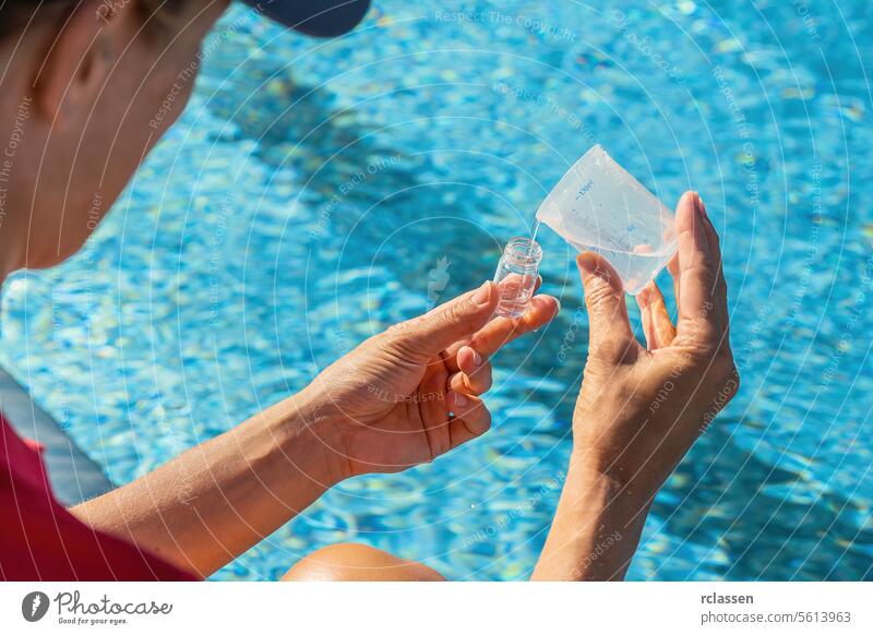 Nahaufnahme von Händen, die Wasser in ein Teströhrchen für einen PH-Wert-Test gießen, vor einem Pool-Hintergrund Abfüllung Prüfung von Schwimmbadwasser