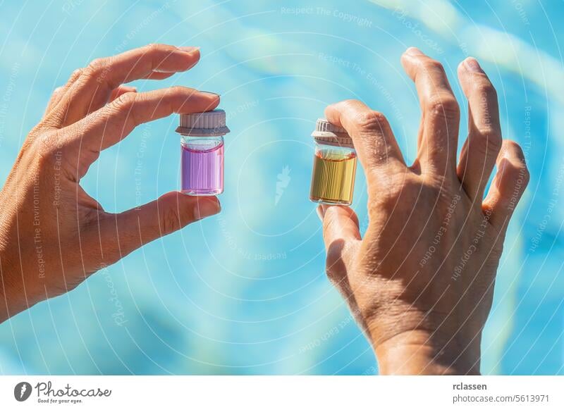 Hände, die Fläschchen mit rosafarbenen und gelben Flüssigkeiten für den pH-Test des Poolwassers in einem Hotel-Wellness-Spa-Resort halten Tintenflüssigkeit