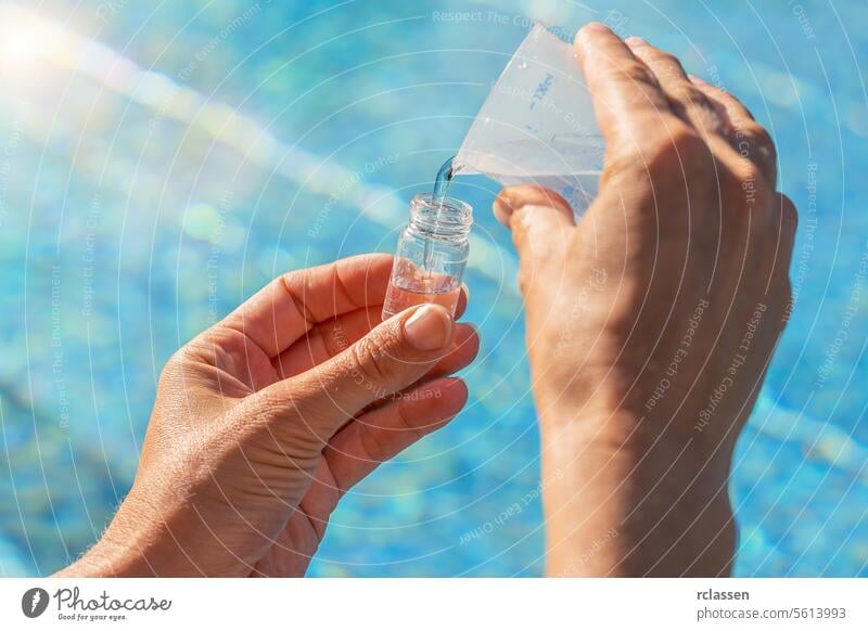 Servicetechniker gießt mit den Händen Wasser in ein Teströhrchen für den PH-Wert-Test vor dem Hintergrund des Schwimmbeckens Abfüllung