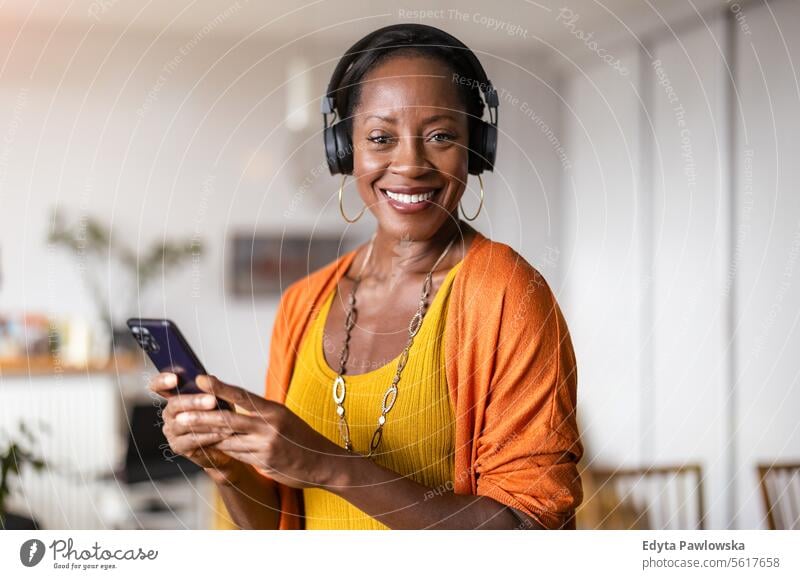 Frau hört Musik mit Kopfhörern im heimischen Wohnzimmer Menschen Freude schwarz natürlich attraktiv schwarze Frau Fröhlichkeit Glück echte Menschen reif