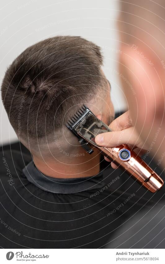 Haarschnitt und Angleichung der Kopfkontur mit einer Haarschneidemaschine (Trimmer). Kurzer Haarschnitt im Friseursalon. Behaarung stylisch Barbershop Stil Mode