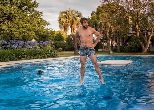 Über Wasser gehen können baden Pool Schwimmen & Baden Sommer Schwimmbad Erfrischung schwimmen Swimmingpool nass Erholung Hund Dackel Palmen junger Mann Badehose