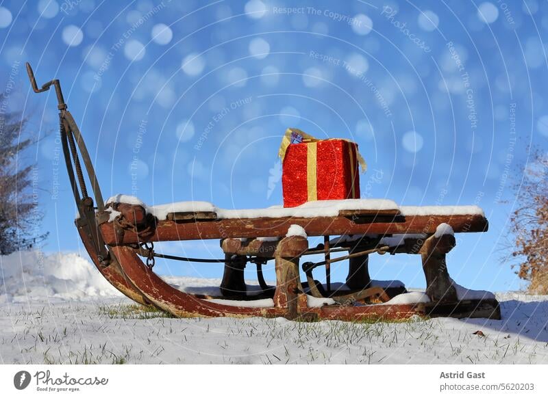 Ein großes rotes Geschenkspaket auf einem Holzschlitten mit Schneekristallen am Himmel geschenk weihnachten winter schnee schneien geschenke geschenkspaket