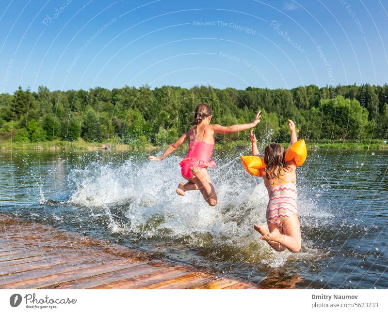 Fröhliche kleine Mädchen, die während der Sommerferien in einem See spielen und ins Wasser springen Seeufer Aktivität sorgenfrei Kind Kindheit Kinder genießen