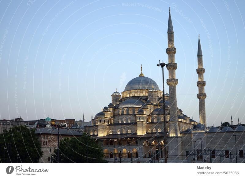 Die angestrahlte Yeni Cami oder Neue Moschee mit Kuppel und Minarett am Abend an der Galatabrücke am Goldenen Horn im Stadtteil Eminönü in Istanbul am Bosporus in der Türkei
