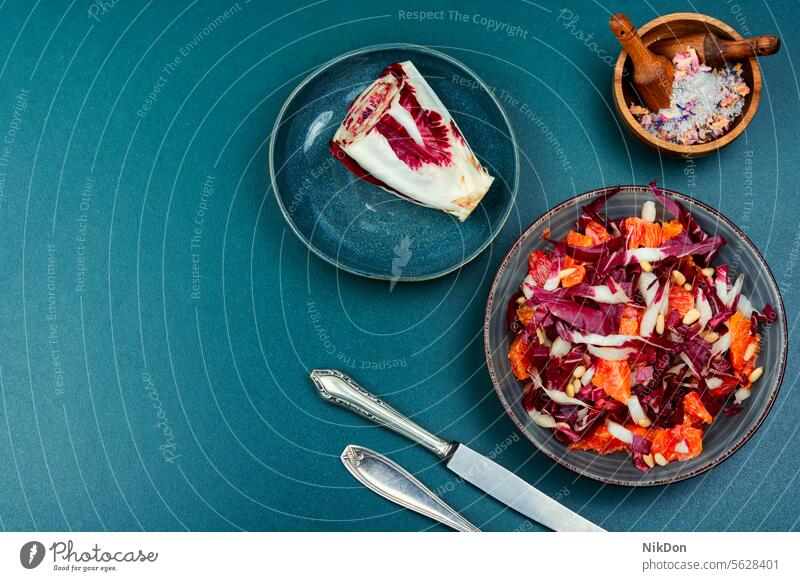 Salat mit orangefarbenem und rotem Bio-Radicchio. Salatbeilage Chicorée Gemüse Vegetarier Gesundheit Lebensmittel rote Zichorie Granatapfel frisch Diät Blatt
