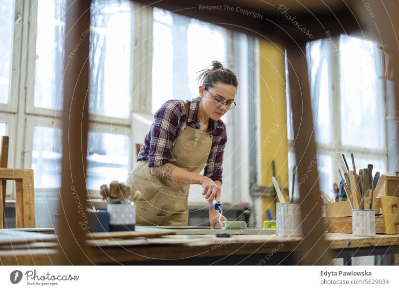 Schreinerin bemalt Möbel in ihrer Werkstatt Zimmerer wiederherstellend Schreinerei Holz Stuhl Gebäude Inszenierung Handwerk Renovierung reparierend Handwerker