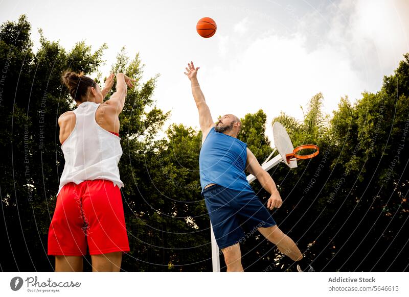 Entschlossener Mann und Frau spielen Basketball auf dem Platz Sportler werfen schießen Reifen springen wehren Ball Athlet Korb Sportpark Gericht Sommer Spiel