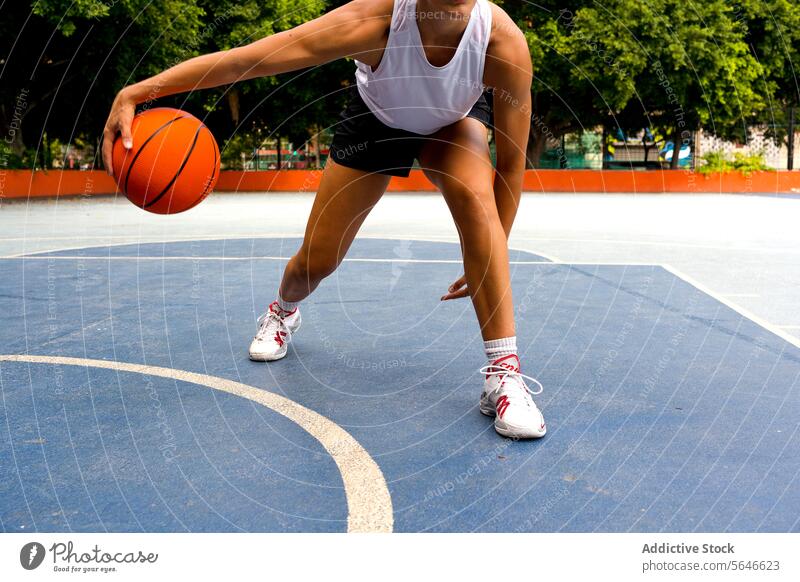 Crop unerkennbar sportliche Frau in activewear dribbeln beim Basketball spielen auf dem Platz während der sonnigen Sommertag Sportlerin Gericht aktiv Ball