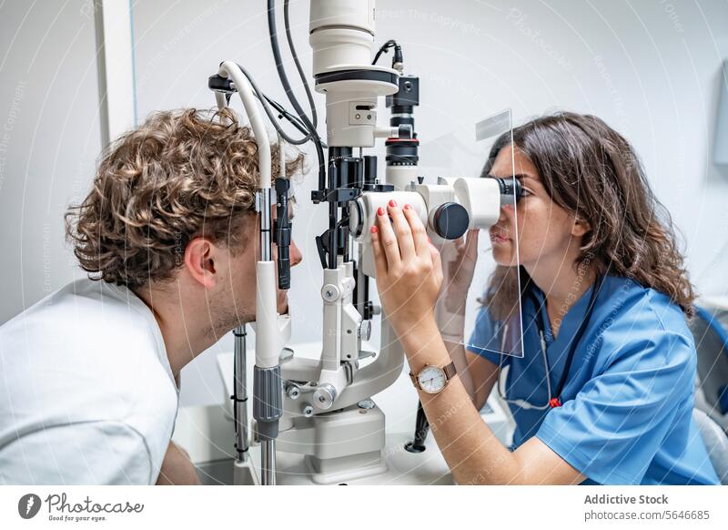 Junge Ärztin untersucht das Auge eines unkenntlichen Mannes in einer Klinik in Lichtern Frau Arzt geduldig Uniform Stethoskop prüfen Spaltlampen-Biomikroskop