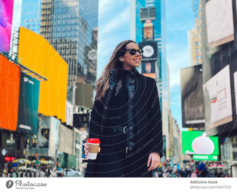 Lächelnde Frau mit Sonnenbrille auf einer Straße in der Stadt heiter Glück Kaffee Großstadt Zahnfarbenes Lächeln genießen urban positiv Optimist froh Tasse jung