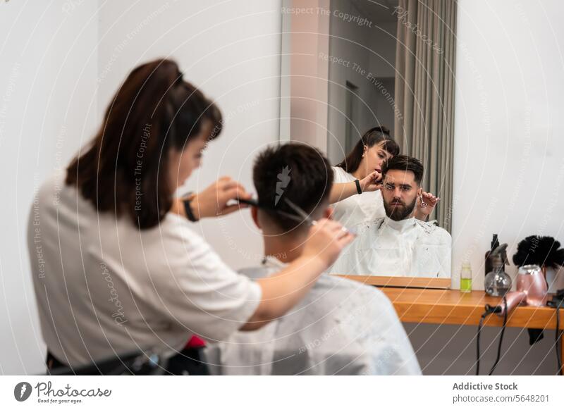 Rückansicht einer Friseurin, die einem männlichen Kunden mit einer Schere die Haare schneidet geschnitten Kamm Mann Salon Behaarung Pflege Dienst Haarschnitt