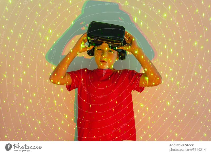 Süßer Junge mit VR-Brille, der in Neonlicht steht und in die Kamera schaut Virtuelle Realität Schutzbrille Headset unterhalten benutzend Gerät
