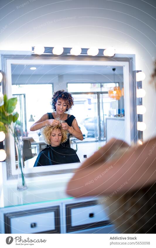 Friseurin, die den Look einer Kundin im Spiegel des Salons entwirft Klient stylen Behaarung lockig Kompetenz Schönheit Reflexion & Spiegelung professionell