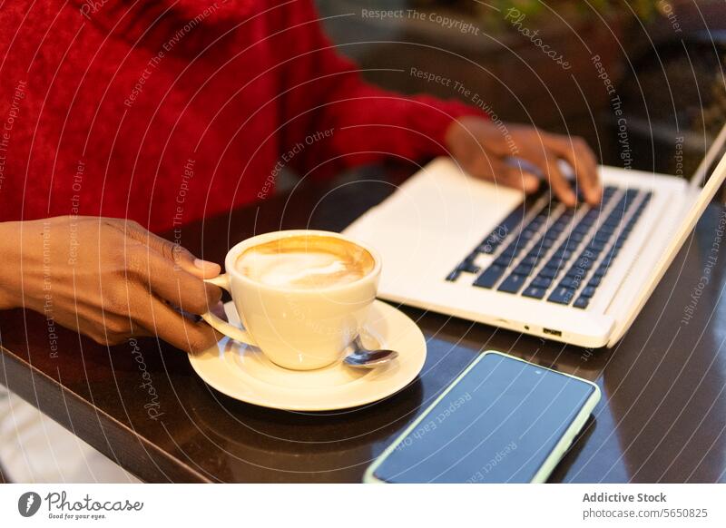 Crop Freiberufler arbeiten am Laptop im Café Frau freiberuflich benutzend trinken Cappuccino Kaffee Tippen Arbeit Erwachsener Afroamerikaner schwarz ethnisch