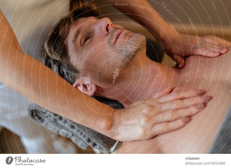 Ein Mann entspannt sich bei einer Brustmassage in einem Spa mit einem gelassenen Gesichtsausdruck.Wellness Hotel Concept image Resort Nackenmassage Nahaufnahme