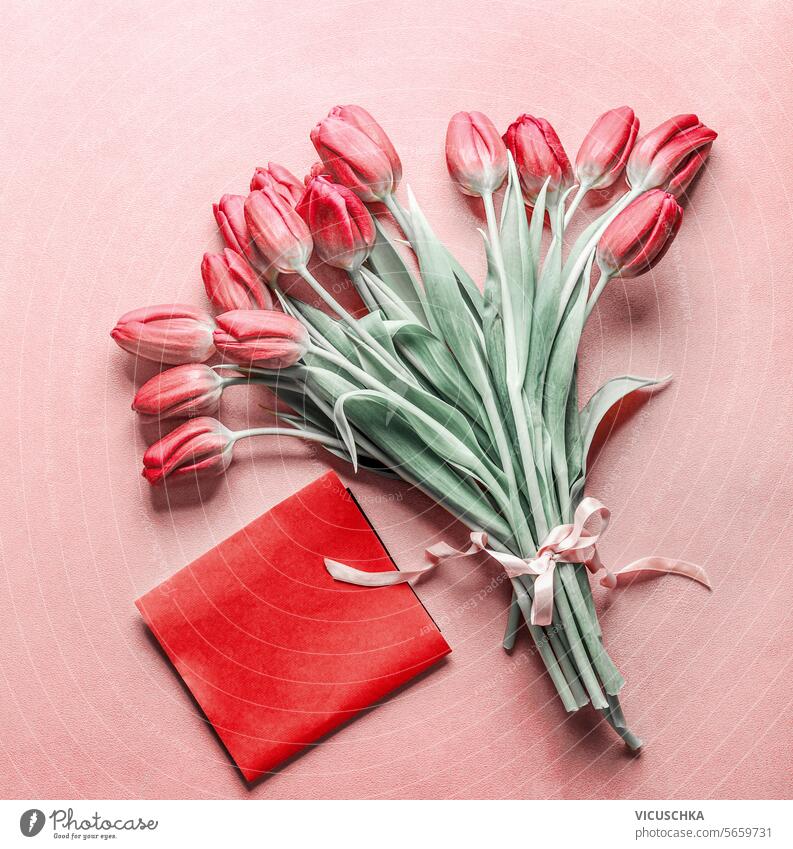 Strauß Tulpen mit leeren roten Grußkarte auf rosa Hintergrund, Ansicht von oben. Valentinstag Konzept Haufen blanko Draufsicht Muttertag Geburtstag Feiertag