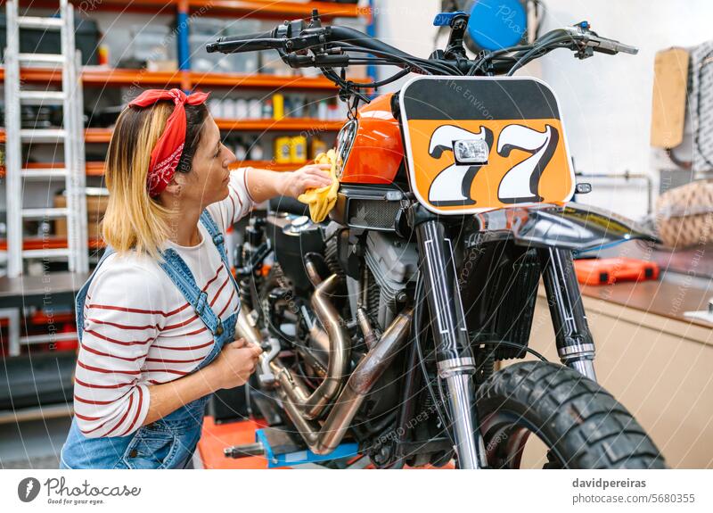 Mechanikerin reinigt Motorrad mit Tuch und Politur in der Fabrik Frau Wischen Reinigen Wäsche waschen Brennstoff Tank Raumpfleger Stoff polnisch Flugzeugwartung
