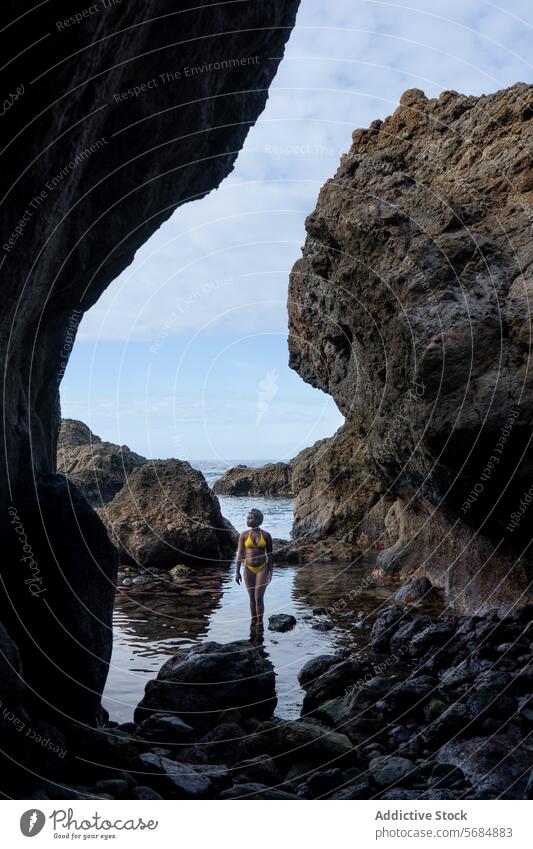 Junge schwarze Frau im Bikini auf einem Stein stehend Tourist Höhle Felsen Badebekleidung felsig Klippe vulkanisch Formation jung MEER Natur Küste Blauer Himmel