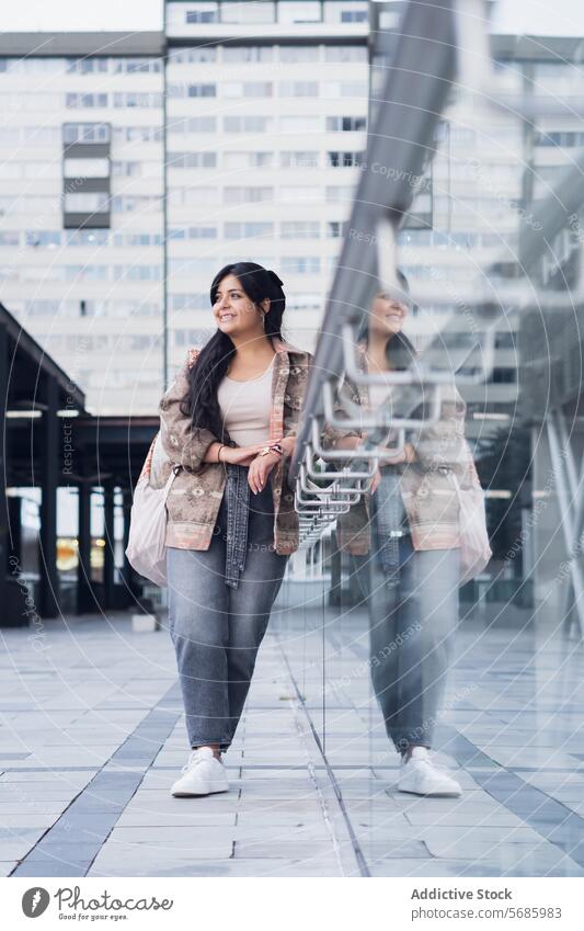 Stilvolle junge Frau auf der Straße selbstbewusst Top kurvenreich Turnschuh Jeanshose stehen Lächeln Gebäude Jacke modern urban Outfit Großstadt Glück