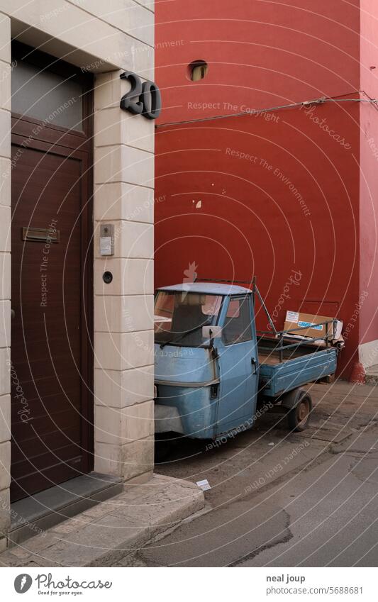 Hellblaues Ape Dreirad im Hinterhof vor roter Hauswand Fahrzeug Italien Kleinkraftrad typisch Klischee einfach Menschenleer authentisch alt shabby unkompliziert