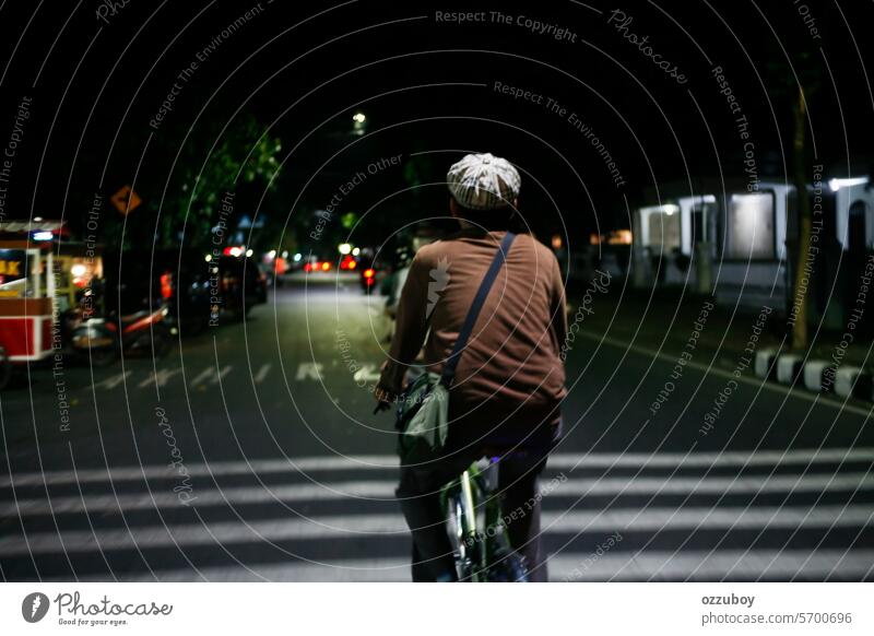 Rückansicht eines Mannes auf einem Fahrrad mitten auf der Straße bei Nacht Menschen Erwachsener eine Person Fahrradfahren im Freien junger Erwachsener