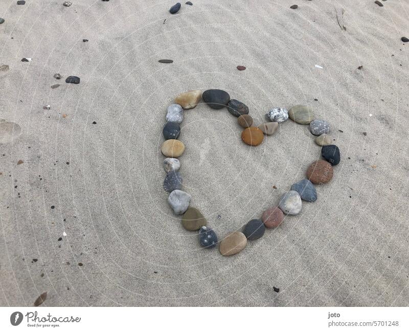 Buntes Herz aus Steinen auf einem welligen Sandstrand herzförmig herzform Liebe wellenförmig Wellenlinie Strand Urlaubsgrüße Urlaubsstimmung Liebeserklärung