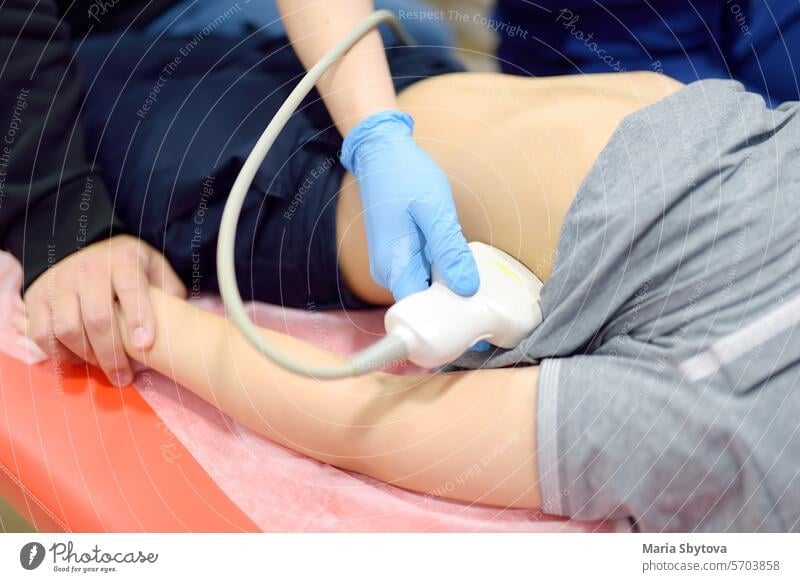 Arzt macht Bauch-Ultraschall für Jungen mit Scanner-Maschine. Weibliche doc läuft Ultraschall-Sensor über Patienten Bauch. Mutter unterstützt Sohn während der Diagnose Untersuchung der inneren Organe
