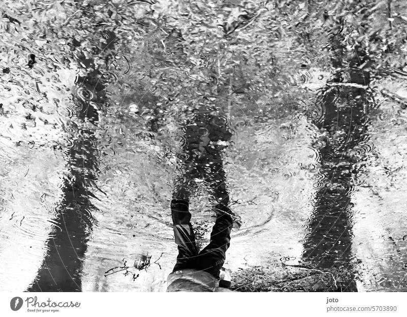 Spiegelung eines Kindes in einer Pfütze an einem verregnetem Tag Spiegelung im Wasser regnerisch regnerisches Wetter Herbst herbstlich herbstliche Stimmung