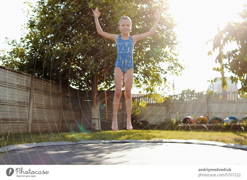 kleine Sport Mädchen springt auf einem Trampolin. Outdoor-Aufnahme von Mädchen springen auf Trampolin, genießt Springen in der Heimat. glückliche Sommerferien