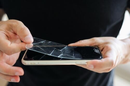 Prozess unerkennbar Techniker entfernt gebrochen und alt gehärtetem Glas Bildschirmschutz von Smartphone, Nahaufnahme. Dienstleistungen zum Kleben und Ersetzen von beschädigtem Schutzglas.