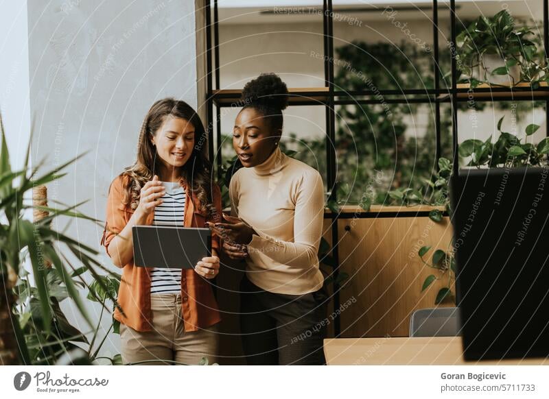 Zwei junge Geschäftsfrauen mit digitalem Tablet stehen im modernen Büro Erwachsener Afrikanisch Amerikaner schwarz Business Geschäftsmann Geschäftsleute