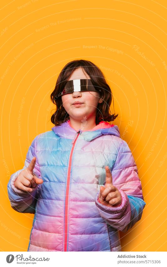 Kind mit pastellfarbener Jacke und futuristischer Brille, das mit dem Finger auf einen orangefarbenen Hintergrund zeigt Zeigen Pastell oranger Hintergrund Mode