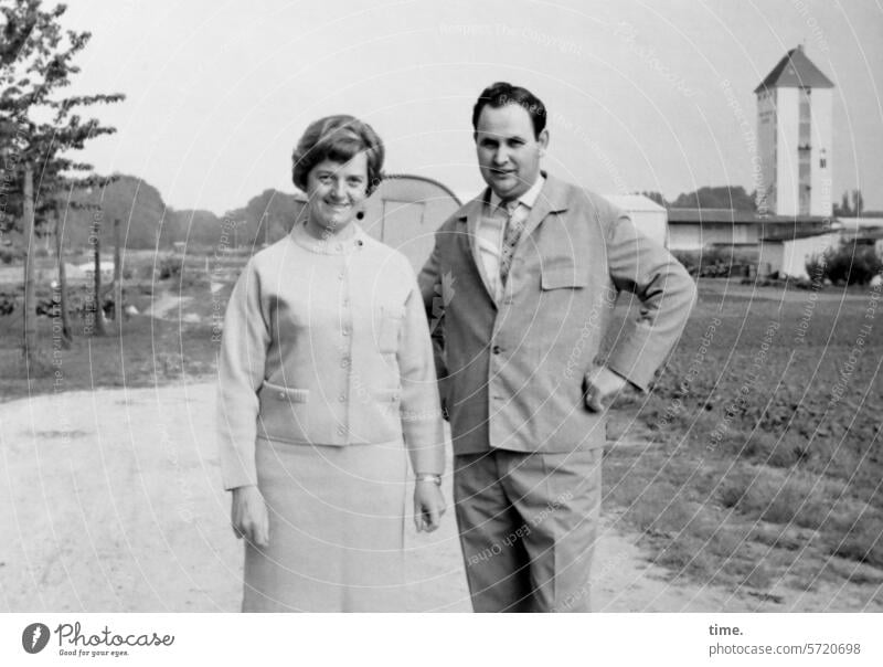 Mann ohne Stativ und Kamera, aber mit Frau, und immer noch an einem Feldweg Landschaft Acker Horizont Stadtrand Turm Architektur Jacke Blick in die Kamera