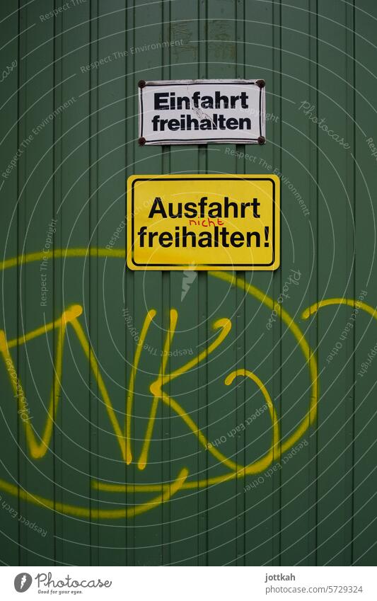 Grünes Garagentor mit zwei Hinweisschildern Deutschland Schild Schilder Einfahrt Ausfahrt Graffiti Schildbürger deutsch spießig freihalten Parkverbot parken