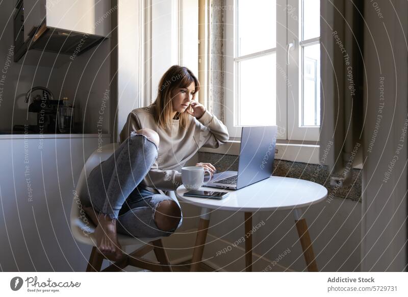 Nachdenkliche Frau arbeitet von zu Hause aus am Fenster Laptop Kaffee Tisch arbeiten heimwärts nachdenklich Sitzen jung Technik & Technologie Internet abgelegen