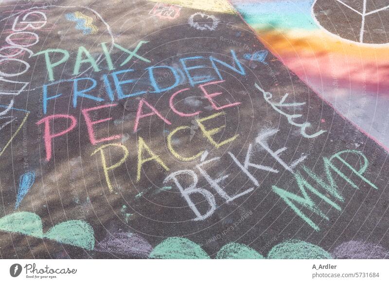 Schriftzüge Frieden, Paix, Peace, Pace, Мир mit farbiger Kreide auf Asphalt gemalt zusammenhalt zeichen freundschaft regenbogenfarben Demonstration