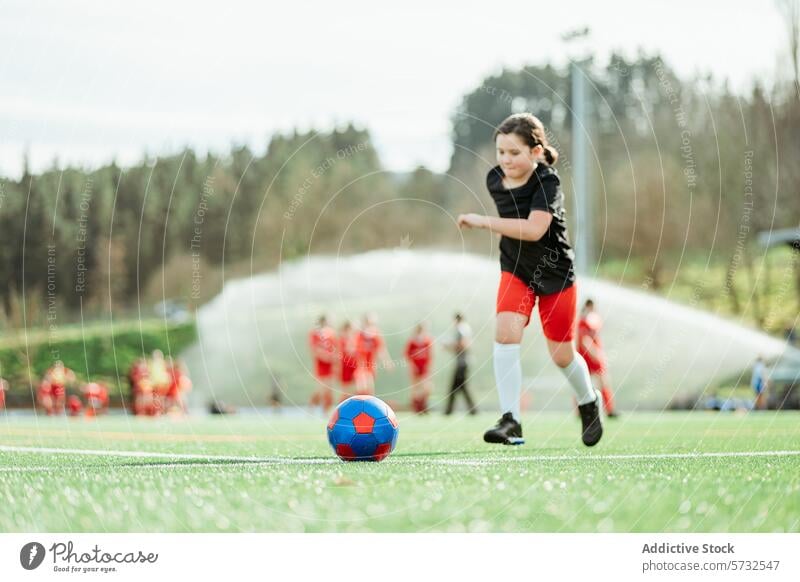 Junger Fußballspieler dribbelt den Ball auf dem Feld Mädchen Dribbling Sport jung Spieler Team Hintergrund sonnig Tag grün Gras Selbstvertrauen Jugend im Freien