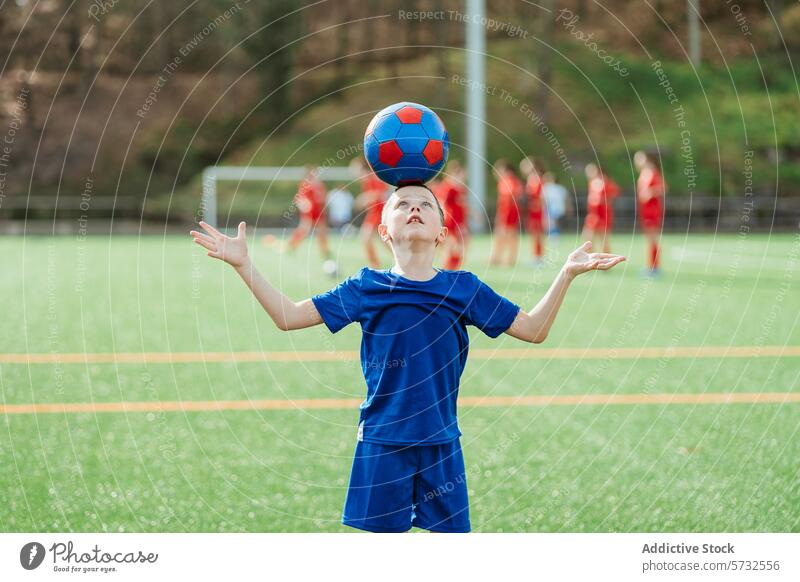 Junger Fußballspieler balanciert Ball auf der Stirn jung Spieler Ausgewogenheit Fokus üben Hintergrund Sport Jugend Training Fähigkeit Feld im Freien Sommer