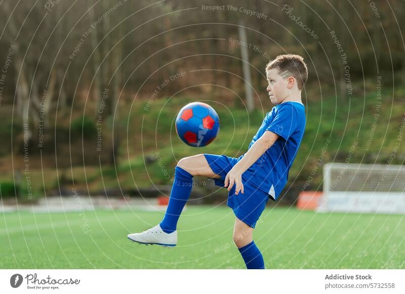 Junger Fußballspieler kontrolliert geschickt den Ball Spieler jung Kontrolle Sport üben im Freien Feld Uniform blau Fähigkeit Jugend Fokus konzentriert Kind